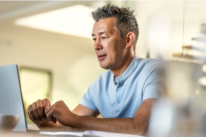 Focused middle-aged man working on a laptop in a modern office