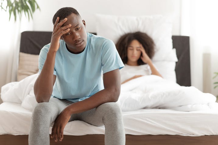 Upset man sitting on the end of the bed