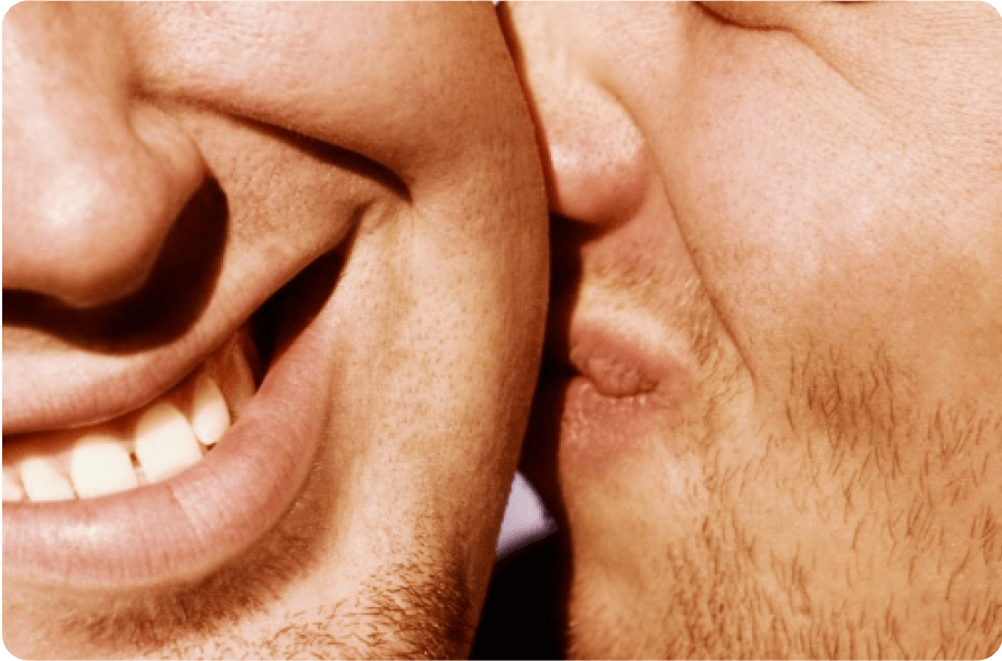 Close-up of two smiling people, focusing on their mouths and cheeks, showing expressions of intimacy